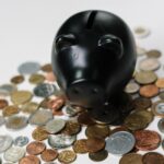 black colored piggy bank on top of a pile of coins